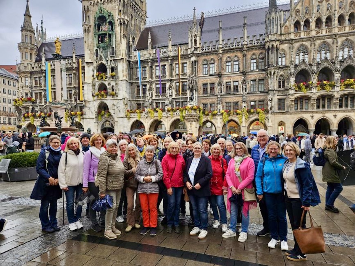 Rund 25 Personen, fast ausschließlich Frauen, haben sich zum Gruppenbild vor dem Münchener Rathaus auf dem Marienplatz aufgestellt. Es hat geregnet, und die Menschen sind warm angezogen.